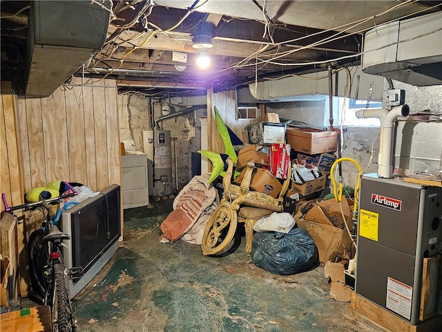 basement featuring wood walls, gas water heater, and washer / dryer