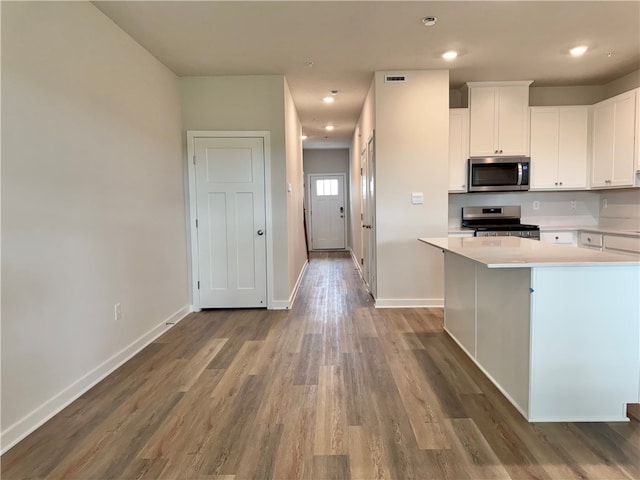 kitchen featuring white cabinets, appliances with stainless steel finishes, and hardwood / wood-style floors