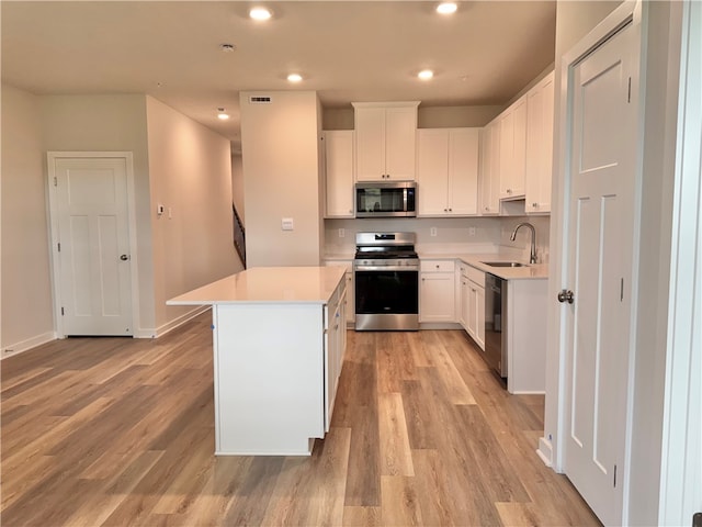 kitchen featuring white cabinets, a kitchen island, sink, and appliances with stainless steel finishes