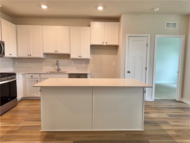 kitchen with white cabinetry, sink, a center island, and appliances with stainless steel finishes