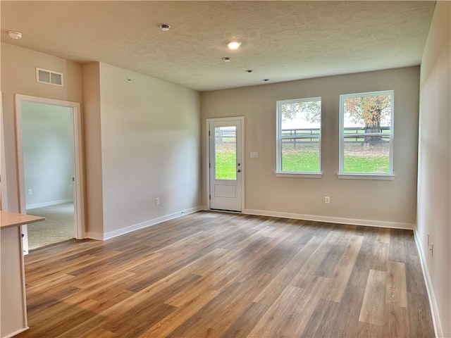 spare room featuring light wood-type flooring and a textured ceiling