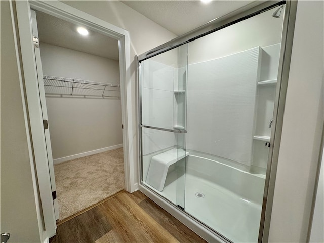 bathroom featuring a textured ceiling, hardwood / wood-style flooring, and a shower with door