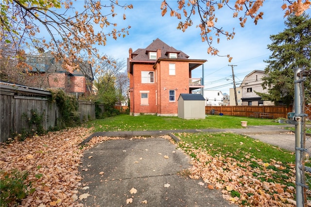 back of house featuring a balcony, a yard, a patio, and a storage unit