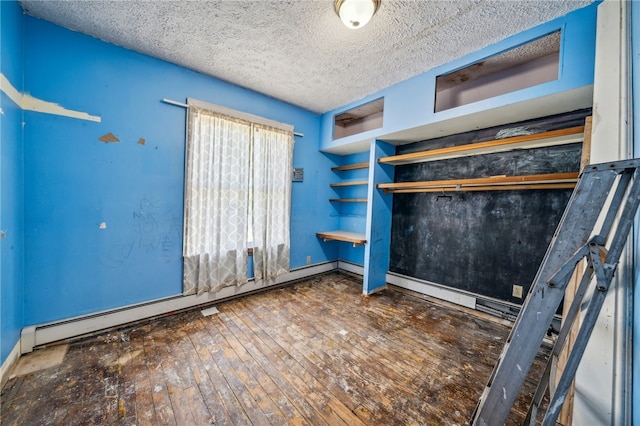 unfurnished bedroom with baseboard heating, a textured ceiling, and dark hardwood / wood-style floors