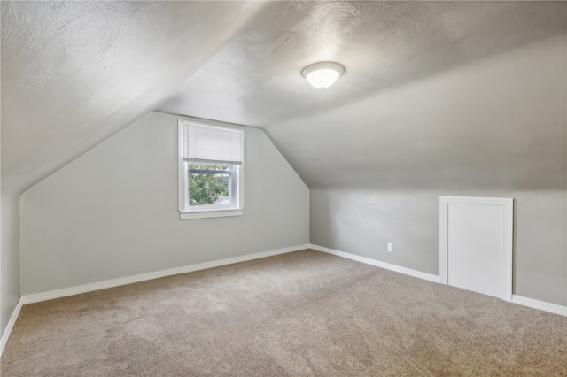 additional living space featuring carpet flooring, a textured ceiling, and vaulted ceiling