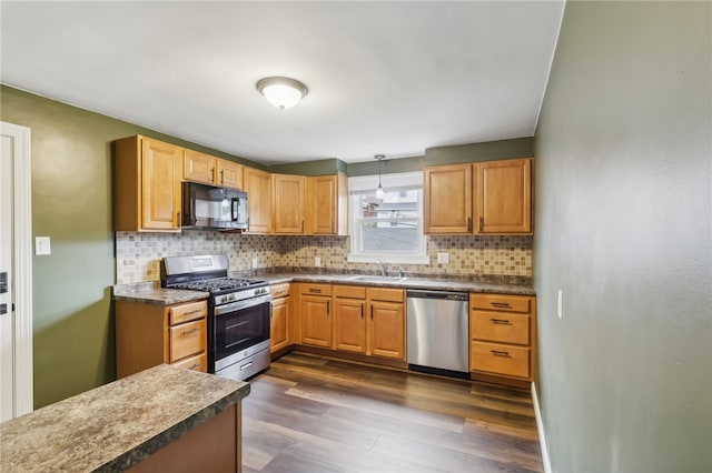 kitchen featuring sink, tasteful backsplash, dark hardwood / wood-style flooring, pendant lighting, and appliances with stainless steel finishes