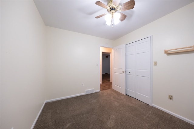 unfurnished bedroom with a closet, dark carpet, and ceiling fan