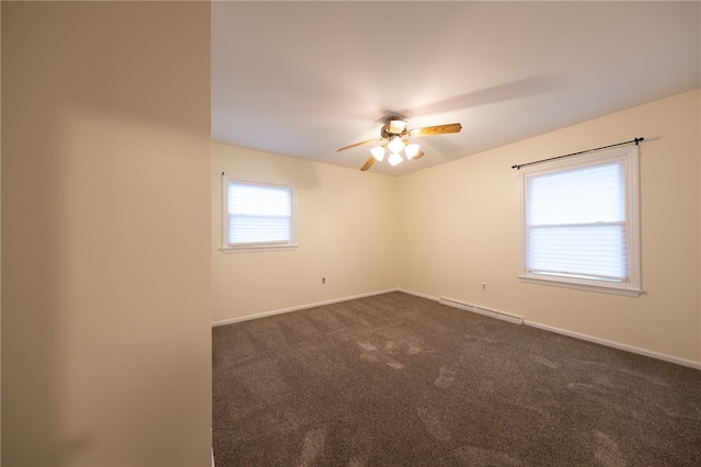 carpeted spare room with ceiling fan, plenty of natural light, and a baseboard heating unit