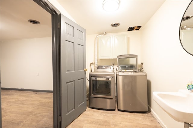 washroom featuring cabinets, light wood-type flooring, separate washer and dryer, and sink