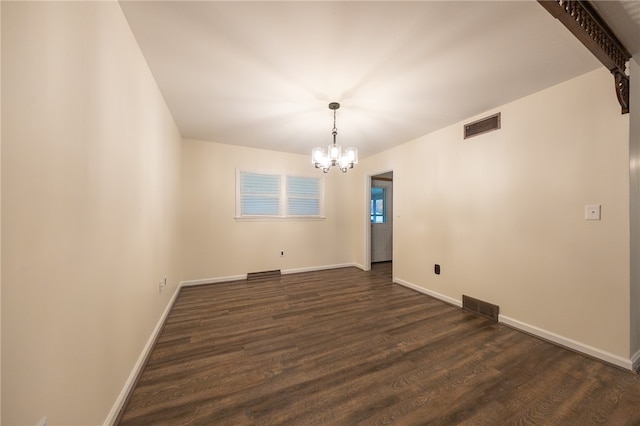 unfurnished room featuring dark wood-type flooring and an inviting chandelier