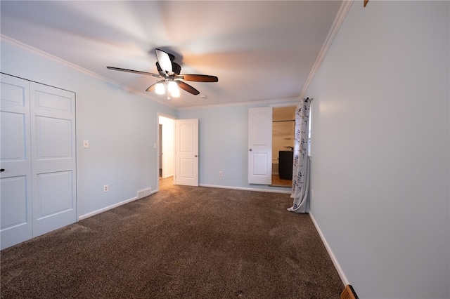 unfurnished bedroom with dark colored carpet, a closet, ceiling fan, and crown molding