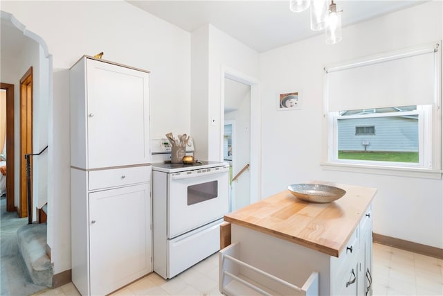 kitchen featuring butcher block counters, electric range, a center island, and white cabinets