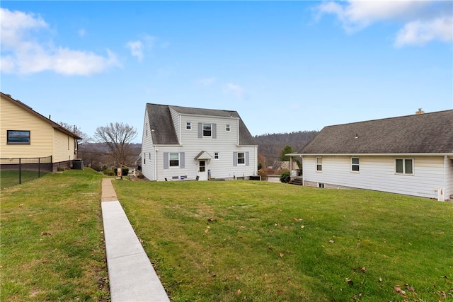 rear view of property featuring a yard and central air condition unit