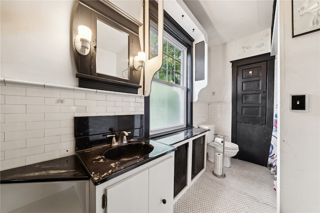 bathroom with vanity, toilet, and tile walls