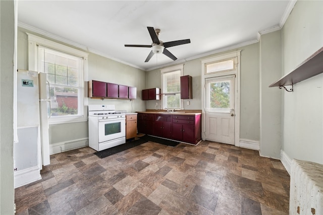 kitchen featuring ceiling fan, a healthy amount of sunlight, ornamental molding, and gas range gas stove