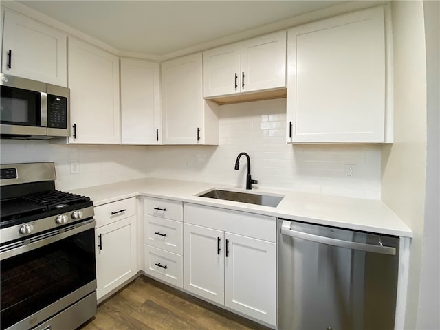 kitchen featuring appliances with stainless steel finishes, tasteful backsplash, sink, white cabinets, and dark hardwood / wood-style floors