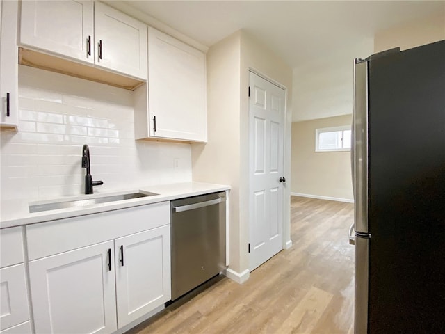 kitchen featuring white cabinetry, sink, light hardwood / wood-style flooring, backsplash, and appliances with stainless steel finishes