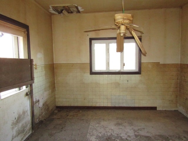 spare room featuring ceiling fan and tile walls