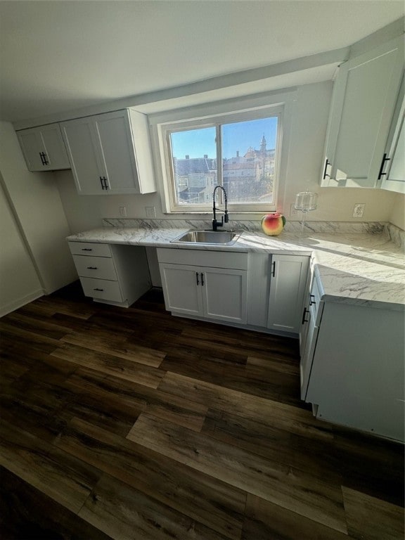 kitchen with white cabinetry, sink, light stone countertops, and dark hardwood / wood-style floors