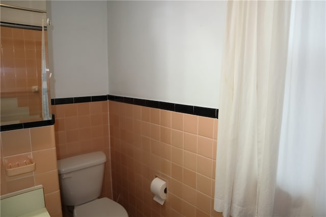 bathroom with tile walls and toilet