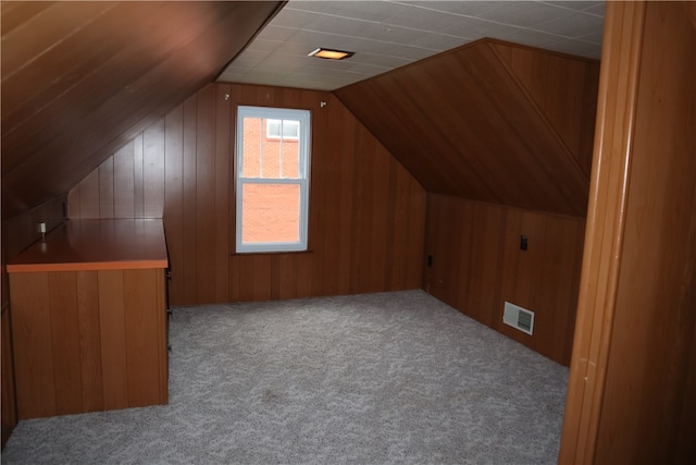 bonus room featuring carpet flooring, lofted ceiling, and wood walls