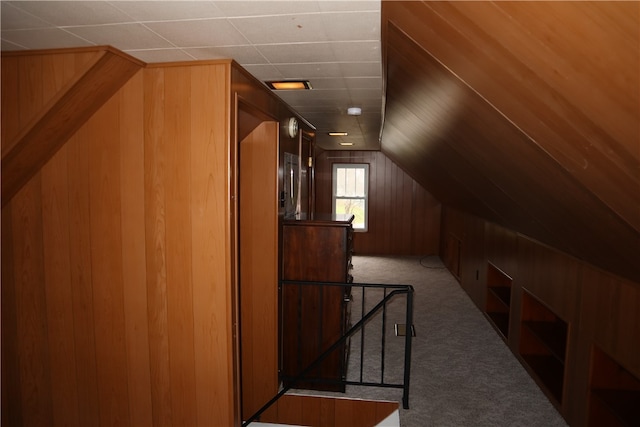 additional living space featuring wood walls, light colored carpet, and vaulted ceiling