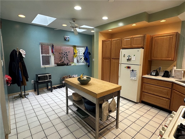 kitchen with ceiling fan, white fridge, light tile patterned floors, and range