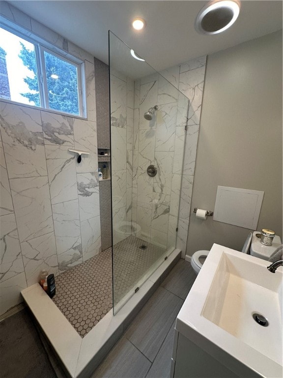 bathroom featuring a tile shower, tile patterned floors, sink, and toilet