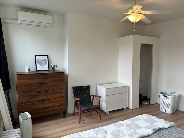 bedroom with light wood-type flooring, a wall unit AC, and ceiling fan