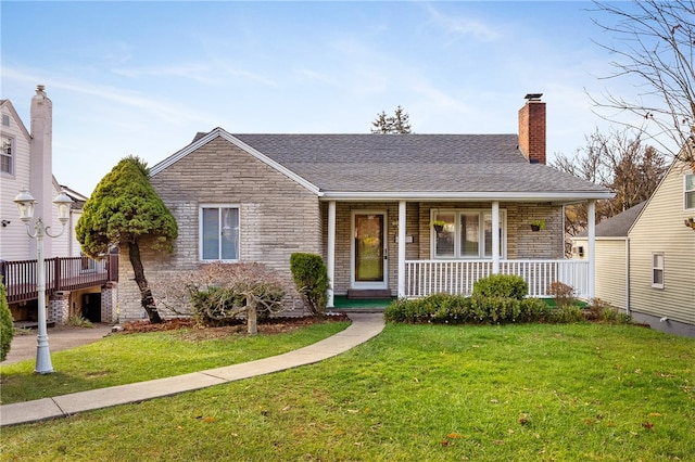 view of front of house with a porch, brick siding, a chimney, and a front lawn