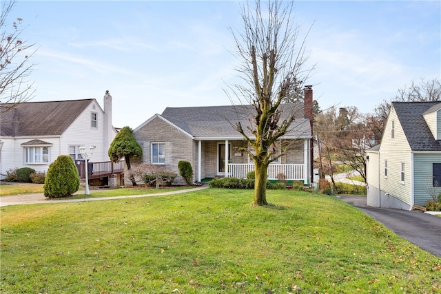 view of front of property with covered porch, a front lawn, and brick siding