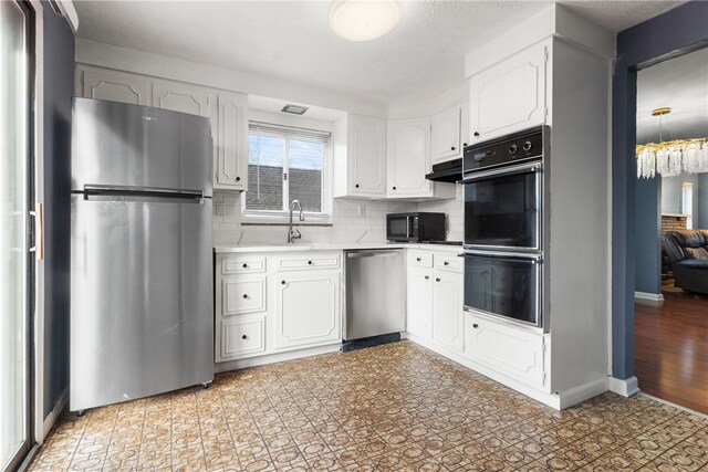 kitchen featuring light floors, light countertops, white cabinetry, under cabinet range hood, and black appliances