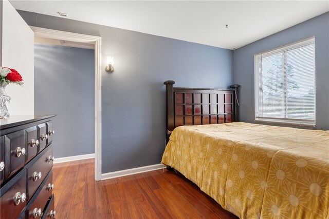 bedroom with baseboards and dark wood-style flooring