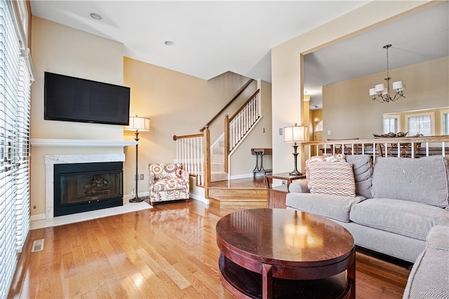 living room with hardwood / wood-style flooring, a notable chandelier, and a fireplace