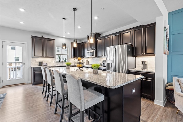 kitchen featuring light hardwood / wood-style floors, a center island, hanging light fixtures, and appliances with stainless steel finishes