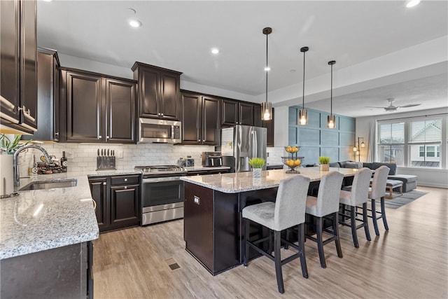 kitchen featuring appliances with stainless steel finishes, light wood-type flooring, ceiling fan, sink, and a kitchen island