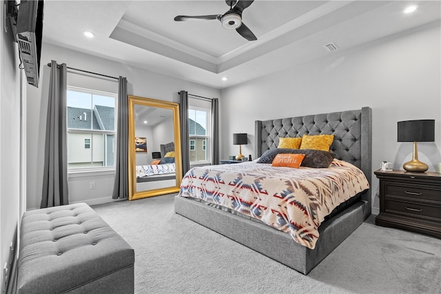 carpeted bedroom featuring a tray ceiling and ceiling fan