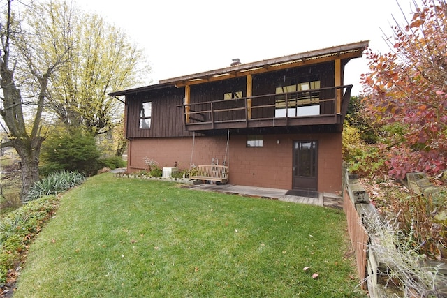 rear view of property featuring a balcony and a lawn