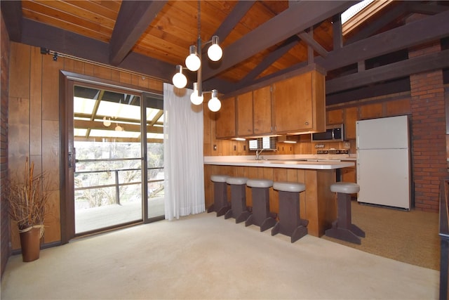 kitchen featuring lofted ceiling with beams, white refrigerator, decorative light fixtures, light colored carpet, and kitchen peninsula