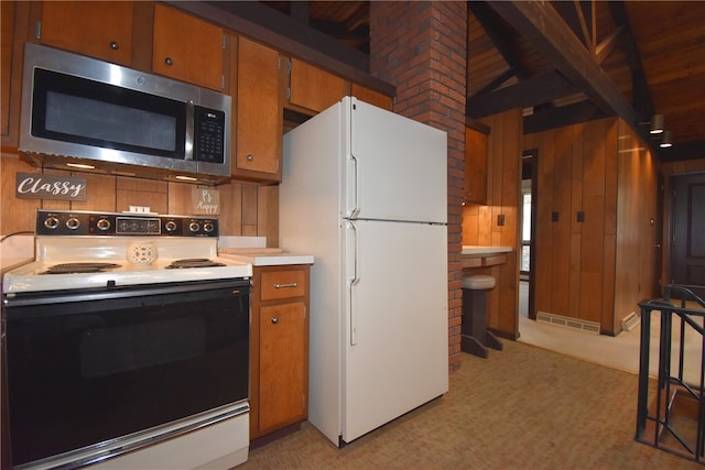 kitchen with beam ceiling, white appliances, and wooden walls