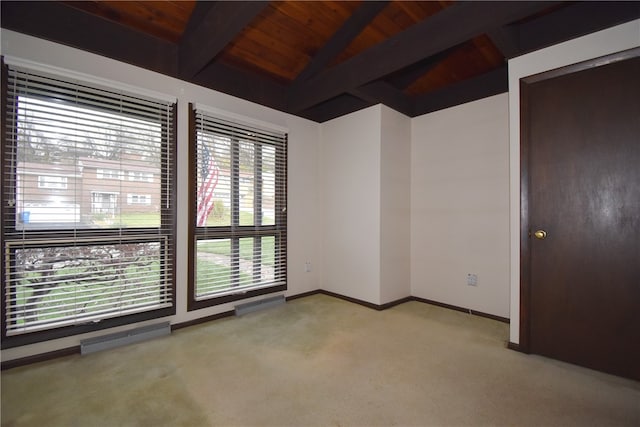 empty room with lofted ceiling with beams, light colored carpet, and wood ceiling