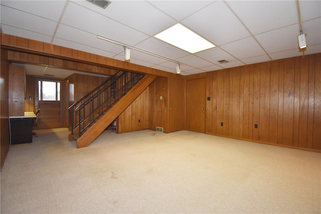 basement featuring light carpet and wood walls