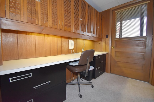 carpeted office space with built in desk and wooden walls