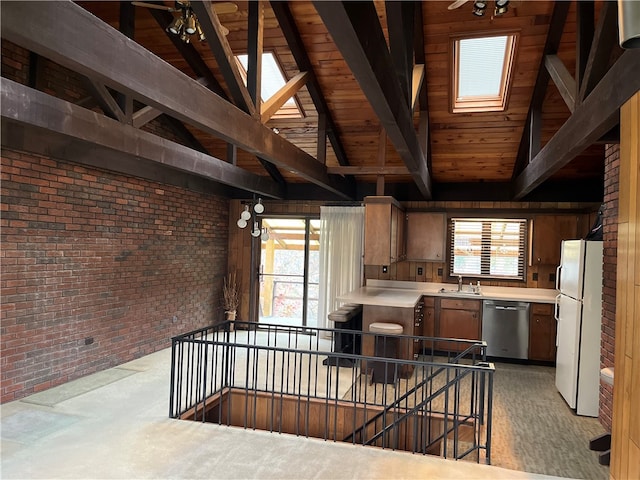 kitchen with white refrigerator, brick wall, sink, and a wealth of natural light