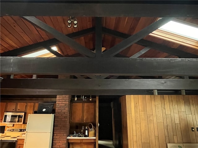 interior space with beam ceiling, white appliances, wood ceiling, and wood walls