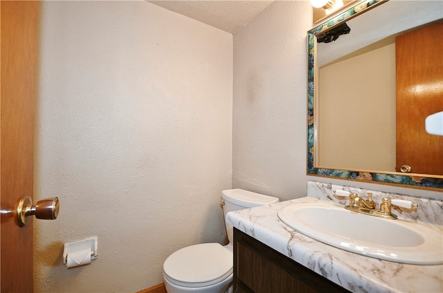 bathroom with a textured ceiling, vanity, and toilet