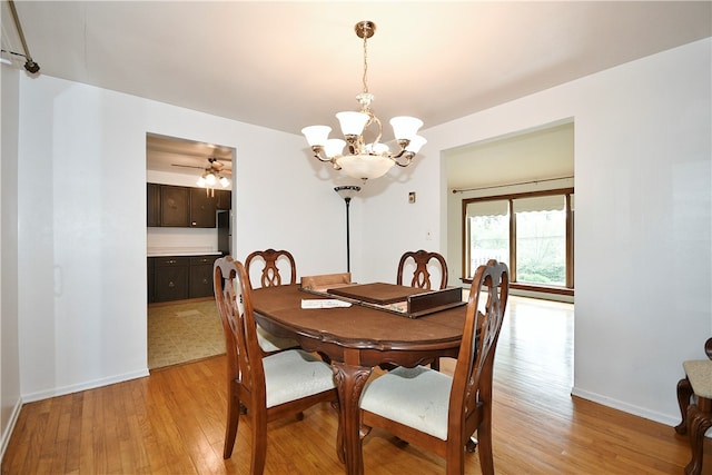 dining room with ceiling fan with notable chandelier and light hardwood / wood-style floors