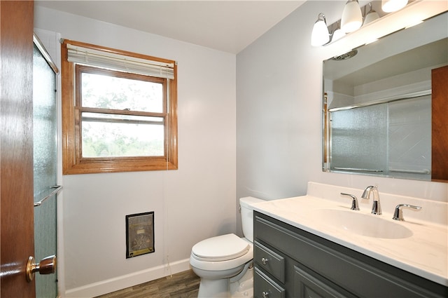 bathroom with hardwood / wood-style floors, vanity, toilet, and a shower with door