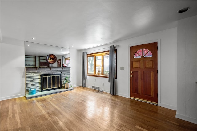 entrance foyer with hardwood / wood-style flooring and a stone fireplace