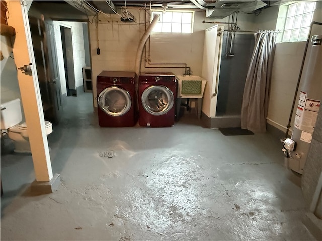 basement featuring washing machine and dryer, sink, and gas water heater